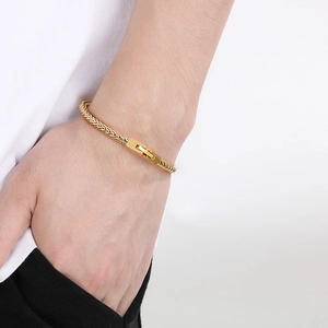 Detail eines goldenen geflochtenen Drachenknochen-Kettenarmbands mit Faltschließe am Handgelenk
