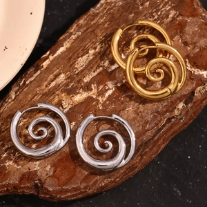 Detail von spiralförmigen Creolen in Gold und Silber auf rustikalem Holzuntergrund