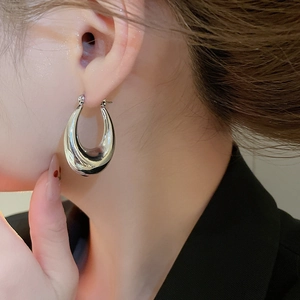 Close-up of chunky silver waterdrop hoop earrings with high-polish mirror finish on model