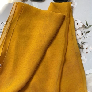 Close-up of ginger yellow silk shawl texture on magazine and soft faux fur rug