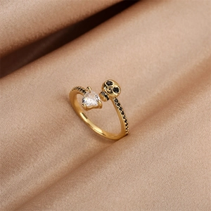 Detail of a gold-plated open ring with heart-shaped zircon and black diamond skull