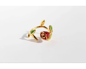 Detailed macro shot of red enamel rose and green leaves on a gold adjustable ring