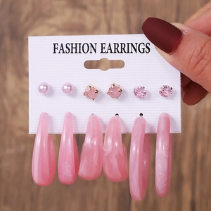 Close-up of 6 pairs of pink stud and hoop earrings set on a white fashion card display