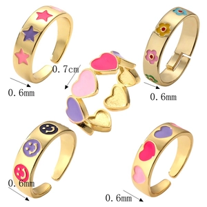 Detail of five adjustable gold-plated rings with colorful enamel heart and star patterns