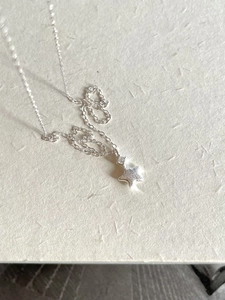 Detailed view of 925 sterling silver star pendant with cubic zirconia on textured paper