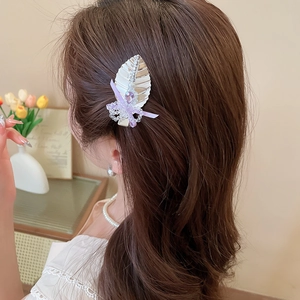 Détail d'une pince à cheveux fleurie avec ruban violet et perles sur modèle
