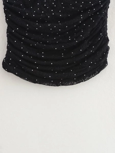 Détail du tissu plissé noir avec des ornements en strass argentés scintillants