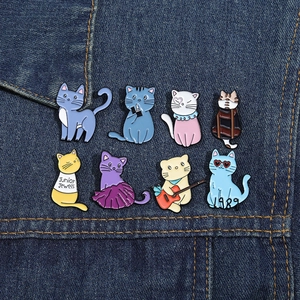 Dettaglio di otto spille in smalto a forma di gatto carino su sfondo in tessuto denim blu