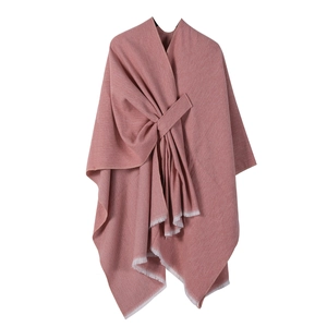 Close-up of pink knitted shawl with elegant tassel edges and soft fabric texture