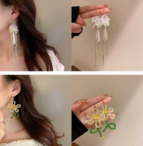 Macro detail of handmade floral pearl earrings with elegant silver tassels and beads