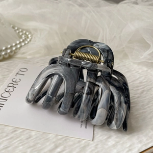 Close-up of a large grey marble acrylic hair claw clip with elegant pearl background