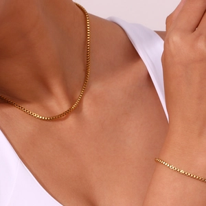Close-up of a minimalist 18K gold plated box chain necklace and bracelet set on model
