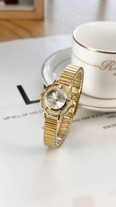 Detail of vintage gold quartz watch with flower-shaped dial and metal spring bracelet