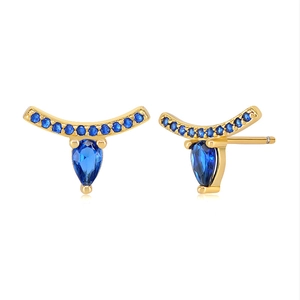 Detailed view of gold earrings with blue pear-cut stones and crystal eyelashes