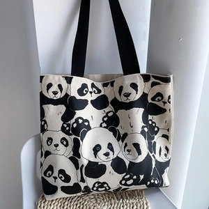 Detail of cute panda print canvas tote bag featuring durable black strap handles