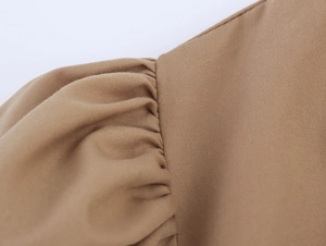Detailed macro view of brown pleated fabric with twill texture and stitching on the dress