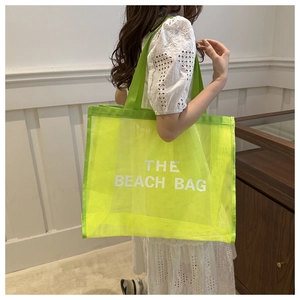 Close-up of neon green mesh tote bag with white THE BEACH BAG lettering in detail