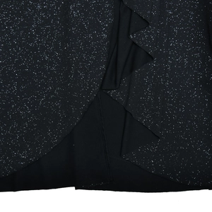 Detail of the black shiny dress fabric featuring silver glitter and ruffled slit design