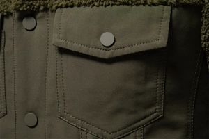 Dettaglio della giacca verde oliva con cuciture in sherpa e tasca cargo militare