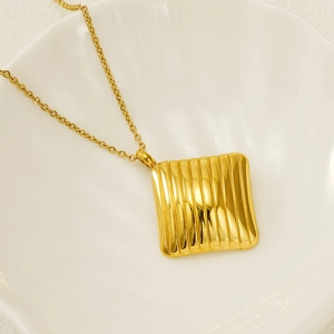 Detailed view of a gold square pendant with vertical stripes on a shell-shaped plate