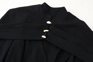 Detail of high neck black top with three irregular gold buttons on fine twill fabric