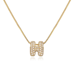 Macro shot of gold-plated H pendant with pavé zircon stones on a fine box chain