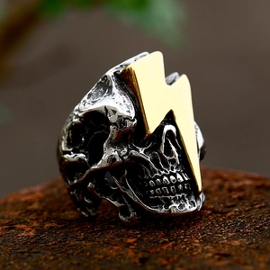 Macro shot of punk skull ring featuring golden lightning details and silver steel finish
