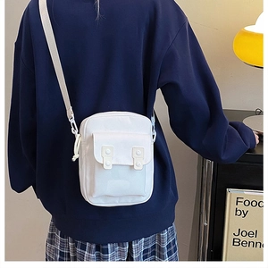 Detailed back view of a white canvas crossbody phone bag on navy sweatshirt