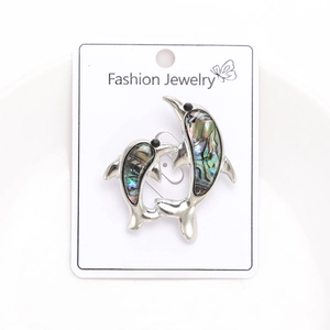 Detail of silver dolphin brooches with colorful abalone shell inlay on display card