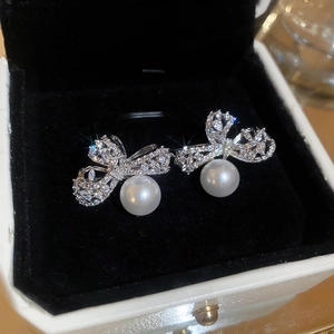 Macro shot of silver bow earrings with pavé crystals and round white pearls