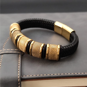 Detail of black woven leather bracelet with gold magnetic clasp on dark leather surface