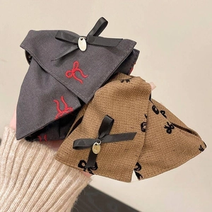 Detail showing grey and brown fabric bow hair clips with gold charms and ribbon