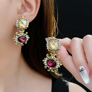 Detailed view of vintage gold earrings with yellow and crimson stones and rhinestones