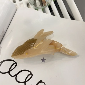 Detail of whale hair claw clip showing marble acetate texture and gold outlines