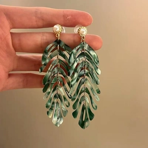 Detail of leaf-shaped earrings with green marble resin, white pearl and gold metal finish