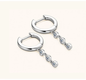 Detailed macro view of silver hoop earrings featuring three stacked round zircon stones