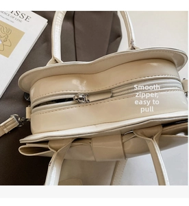 Détail d'un sac à main blanc crème montrant le similicuir lisse et la fermeture éclair argentée