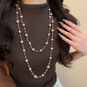 Close-up of a double-layered champagne pearl and crystal necklace on a brown sweater