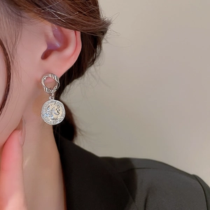 Detail view of silver coin drop earrings featuring a twisted hoop and portrait relief