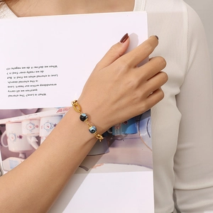 Detail of gold hollow lip charm bracelet with blue marbled resin beads on wrist