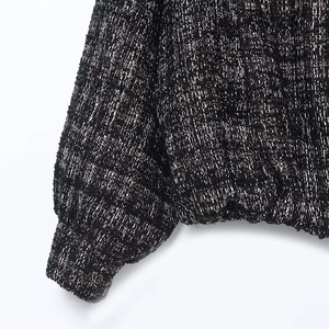 Detailed close-up of black and silver tweed fabric texture on sleeve and hemline