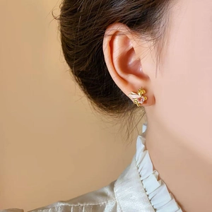 Golden unicorn stud earrings with pink heart gemstone shown on a female model