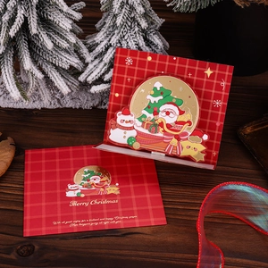 Detail of 3D Christmas card with red plaid design on dark wood table with festive ribbon