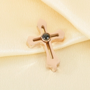 Close-up of rose gold cross pendant with projection stone on beige silk fabric
