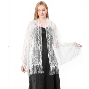 Detailed view of white floral lace shawl with long fringe tassels on black dress
