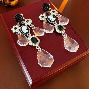 Macro detail of Baroque style drop earrings featuring a cameo portrait and black rose
