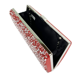 Close-up of red rhinestone clutch bag showing silver clasp and detachable chain strap