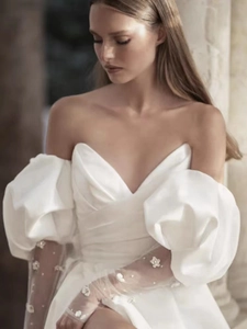Detail of elegant bridal white gown featuring puff sheer tulle sleeves with floral accents