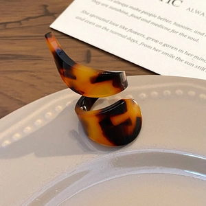 Spiral acrylic tortoiseshell ring with leopard print pattern on beige ceramic plate