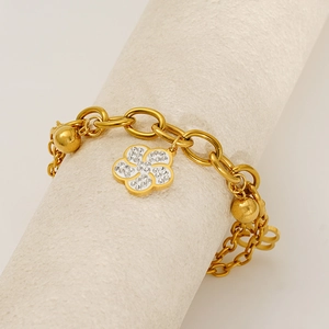 Détail d'un bracelet fleur plaqué or 18k avec cristaux sur un présentoir blanc